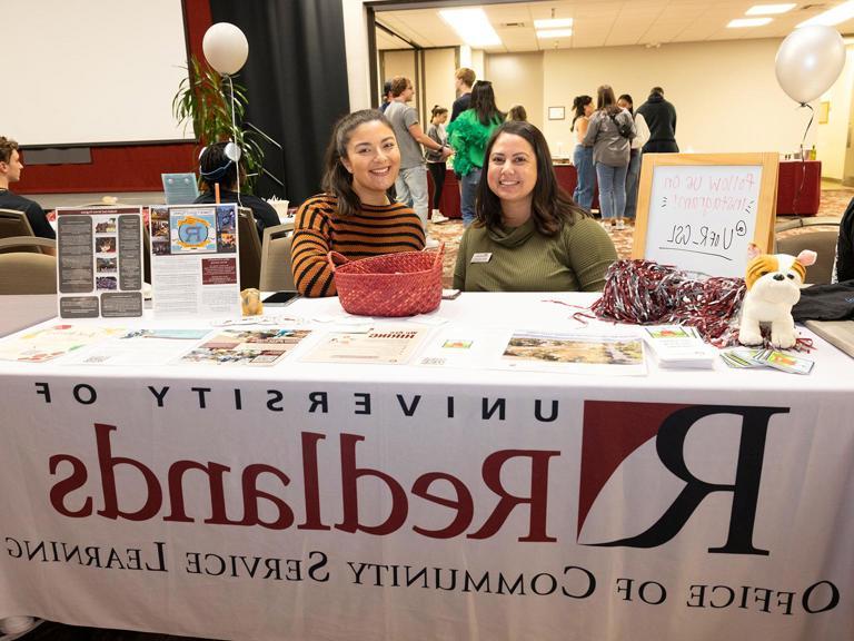 Two Community Service Learning members sitting and advertising internships.